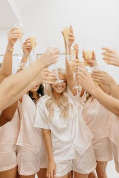 a group of women toasting with champagne glasses in front of their faces and hands