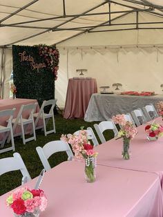 tables and chairs set up in a tent with pink tablecloths on the grass