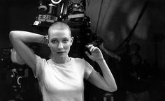 a black and white photo of a woman in front of a camera with her hands behind her head