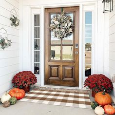 the front door is decorated with pumpkins and flowers