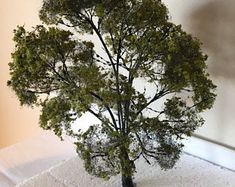 a small tree sitting on top of a table next to a white cloth covered surface