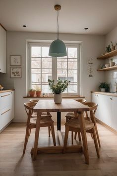 a kitchen with a table and chairs in front of a window that has plants on it