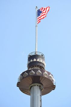 an american flag flying on top of a tall tower