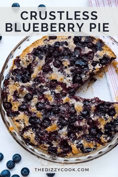 a blueberry pie is cut in half on a white table with berries around it