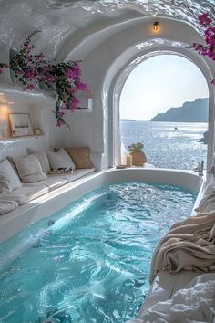 an indoor jacuzzi tub with flowers on the wall and windows overlooking the water