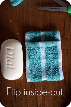 a wooden table topped with blue towels and a white soap bar next to a pair of scissors