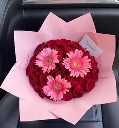 a bouquet of pink and red flowers sitting on top of a car seat