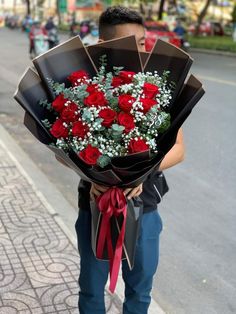 a man holding a bouquet of roses on the street