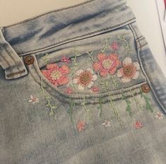 a pair of jeans with flowers embroidered on them