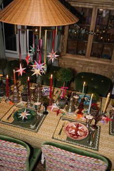 the table is set for christmas dinner with candles and plates on it, along with other holiday decorations