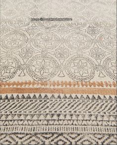 an intricately designed rug with orange and white stripes on the bottom, in front of a