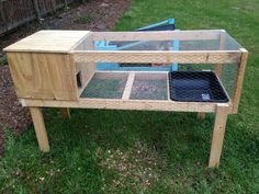 an outdoor rabbit house made out of pallet wood and chicken wire, sitting in the grass