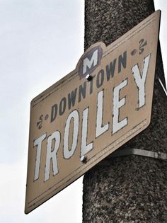 a street sign attached to a tree with the word trollley painted on it's side