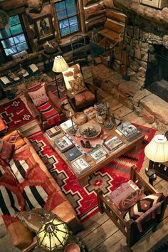 a living room filled with furniture and a fire place next to a stone fireplace in a log cabin