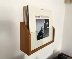 a wooden shelf holding several records on it's side and a magazine rack above it