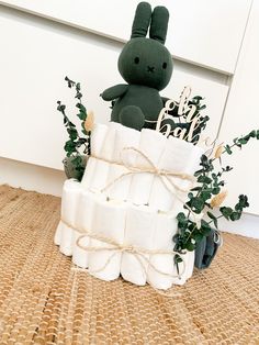 a stuffed rabbit sitting on top of a pile of toilet paper next to a plant