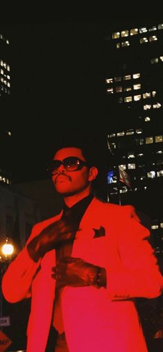 a man in a red suit and sunglasses is posing for the camera with his hands on his chest