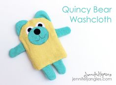 a blue and yellow stuffed animal laying on top of a white surface with the words quincy bear washcloth written below it