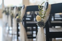 a row of black chairs with white sashes and flowers on them