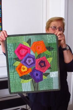 a woman holding up a piece of art with flowers on it