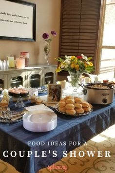 a table filled with food and desserts on top of a blue cloth covered table