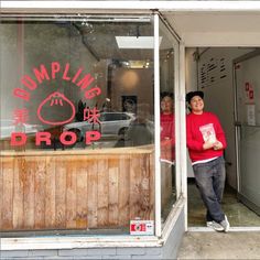 two people are standing in the doorway of a building with a sign on it that says dumpling drop