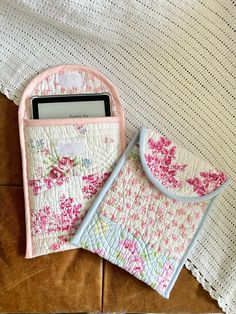 two cell phones sitting next to each other on top of a bed with floral designs