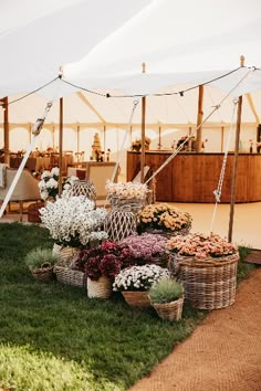 an outdoor tent set up with flowers and baskets