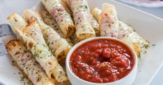 a white plate topped with different types of appetizers next to a bowl of sauce