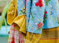 colorful clothing with flowers on them hanging from a rack in front of a store window