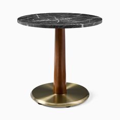 a round marble table with brass base and an oval black marble top on a white background