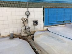 an old water faucet in the middle of a room with tiled walls and flooring