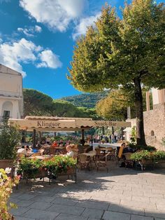 people are sitting at tables under umbrellas on a sunny day in the town square