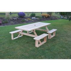 a wooden picnic table sitting on top of a lush green field