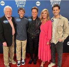 three men and two women posing for a photo on the red carpet