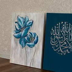 two paintings with arabic writing on them, one is blue and the other has white flowers