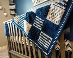 a crocheted blue and white blanket hanging from the side of a crib