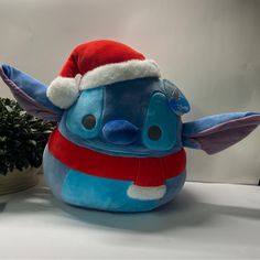 a stuffed animal wearing a santa hat next to a potted plant