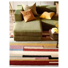 a green couch sitting on top of a colorful rug