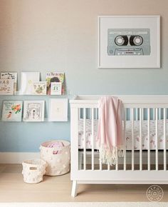 a baby's room with a white crib and pictures on the wall above it