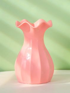 a pink vase sitting on top of a white table