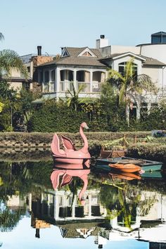 some boats are sitting in the water near houses and palm trees on the other side