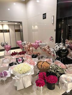 a table filled with lots of different types of flowers and heart shaped balloons on top of it