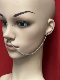 a white mannequin head with piercings on it's nose and eyebrows