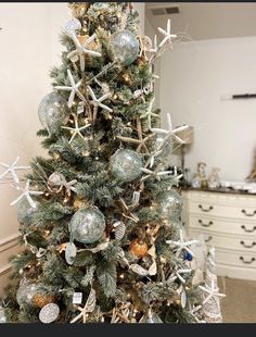 a decorated christmas tree with starfish ornaments and seashells on the top, in a living room