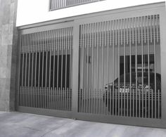 a black and white photo of a car through the bars of a jail cell door