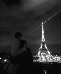 a man and woman standing in front of the eiffel tower