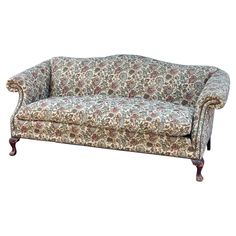 an old fashioned couch with floral fabric and wood legs, sitting on a white background