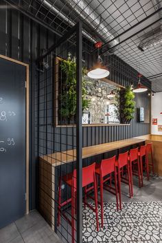 an empty restaurant with red chairs and black partitions on the wall, along with a chalkboard menu