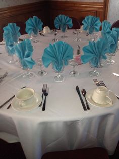 the table is set up with silverware and blue napkins for an elegant dinner